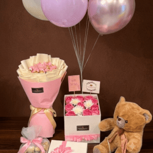 Luxury gift set featuring a brown teddy bear, chocolate bouquet, birthday roses in a box, and colorful balloons against a dark brown background.