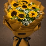 Vibrant sunflower bouquet wrapped in brown paper with a black ribbon.