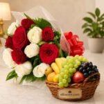 A gift basket with fresh seasonal fruits and a bouquet of roses to send gifts to Lahore.